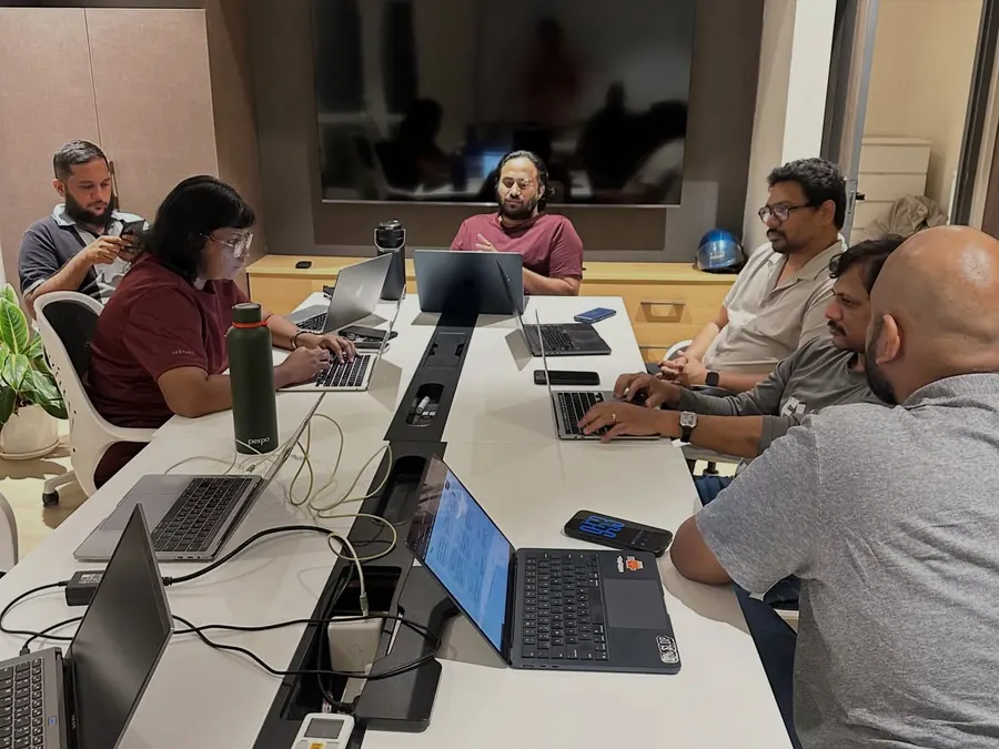 Builders around a boardroom table, one presenting from a laptop