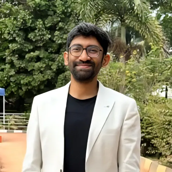 Chandrasekar Jayapalan smiling outdoors in a white blazer and glasses