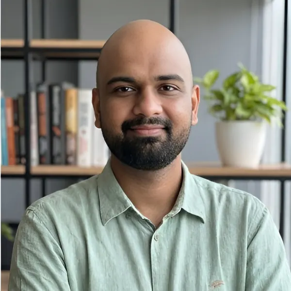 Shankar K in a green linen shirt in front of a bookshelf